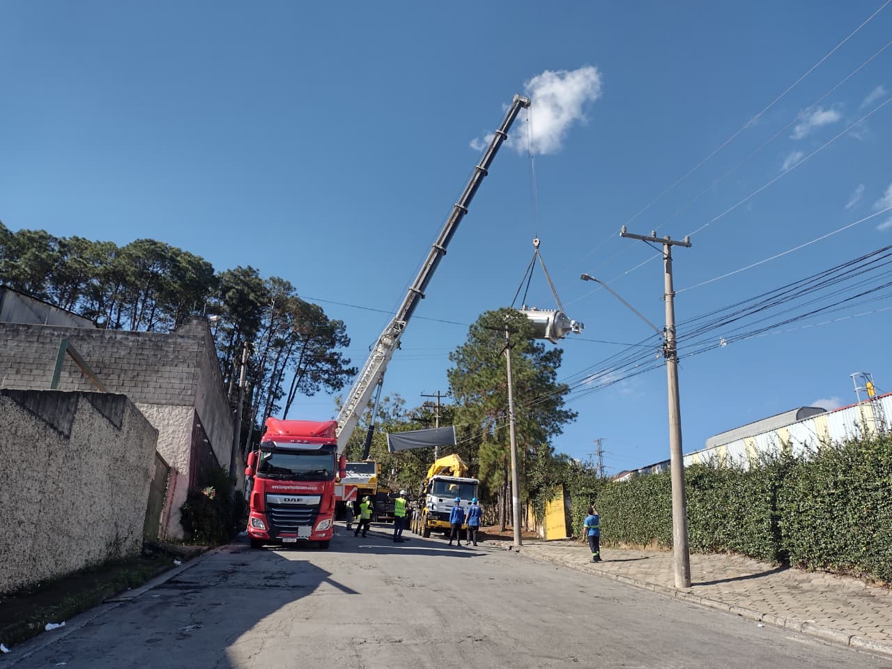 Autoclave suspensa acima da rede elétrica e via pública, com caminhões DAF e Mercedes no solo