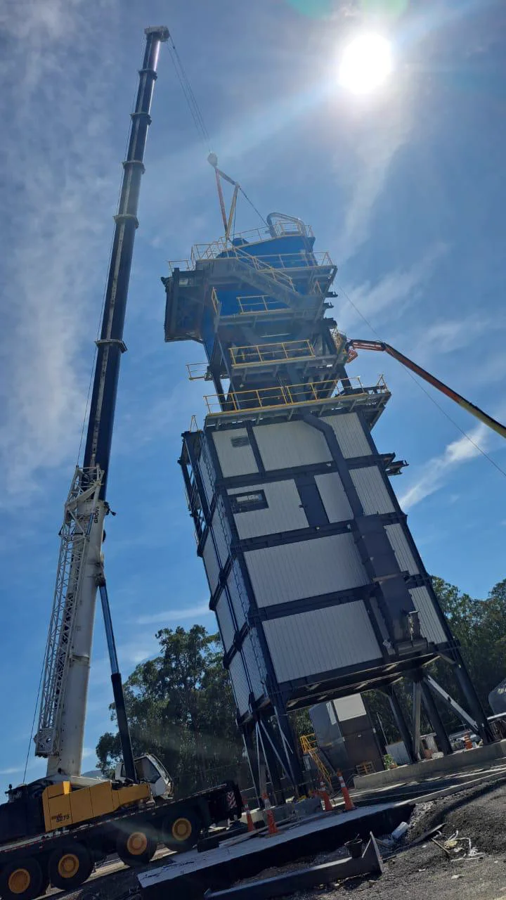 Guindaste com lança estendida junto à estrutura da usina de concreto da Usicon