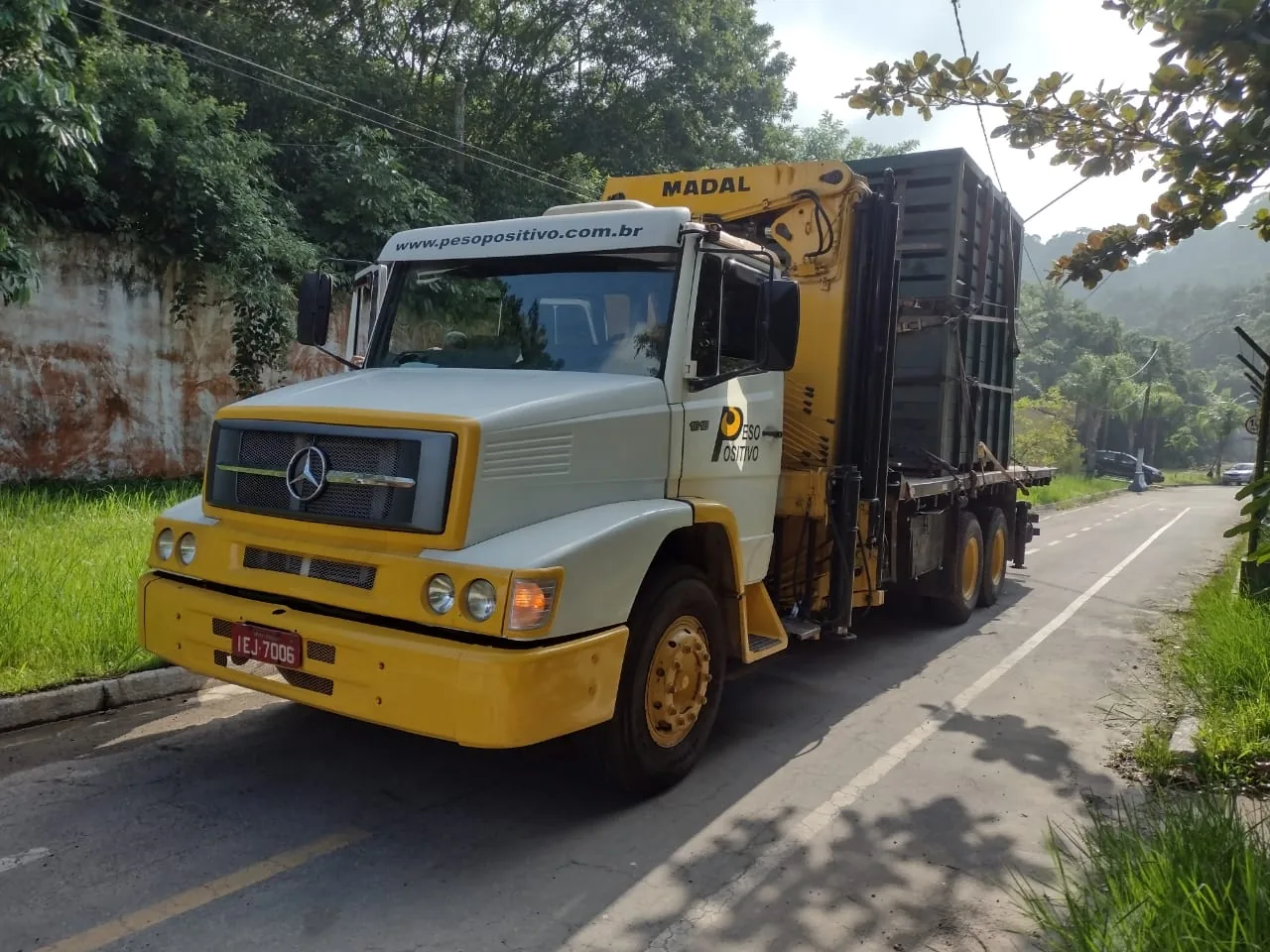 Caminhão do Peso Positivo transportando caixa verde de animais em via interna cercada por mata do Zoológico de São Paulo