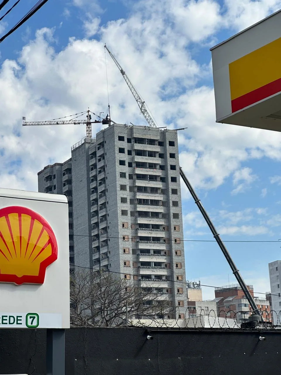 Guindaste telescópico móvel do Peso Positivo com lança e jib estendidos até o topo de edifício em construção para montagem de grua de torre